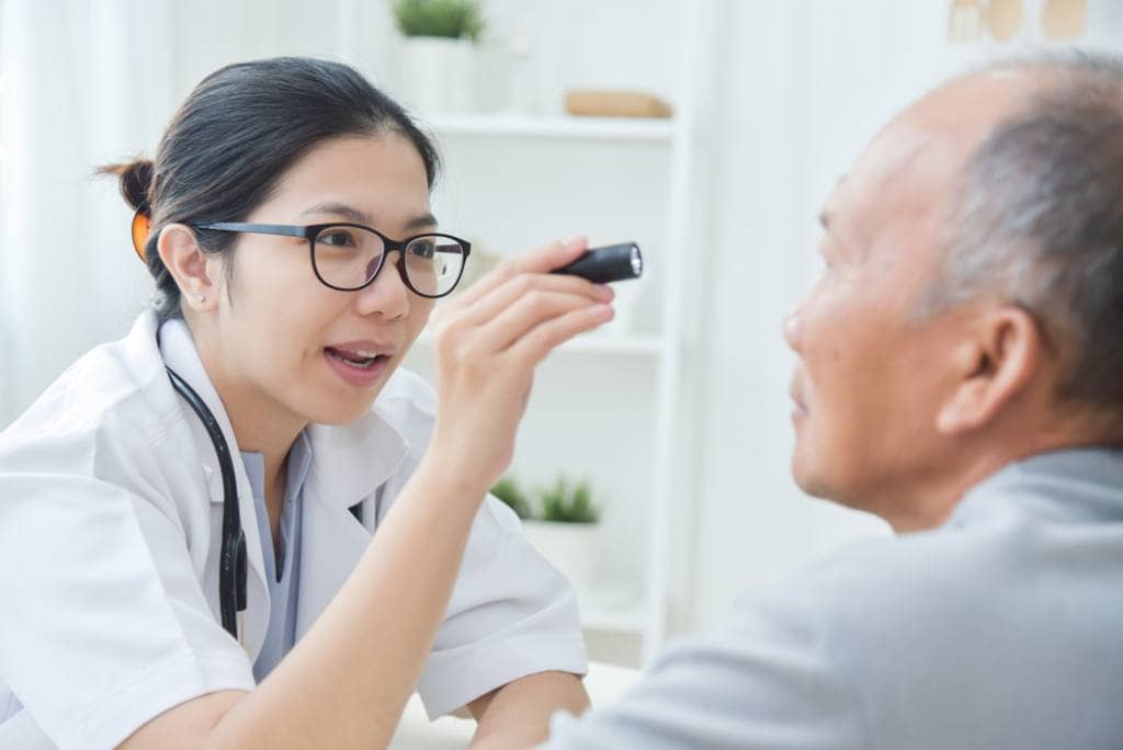 An eye surgeon examines an older patient 